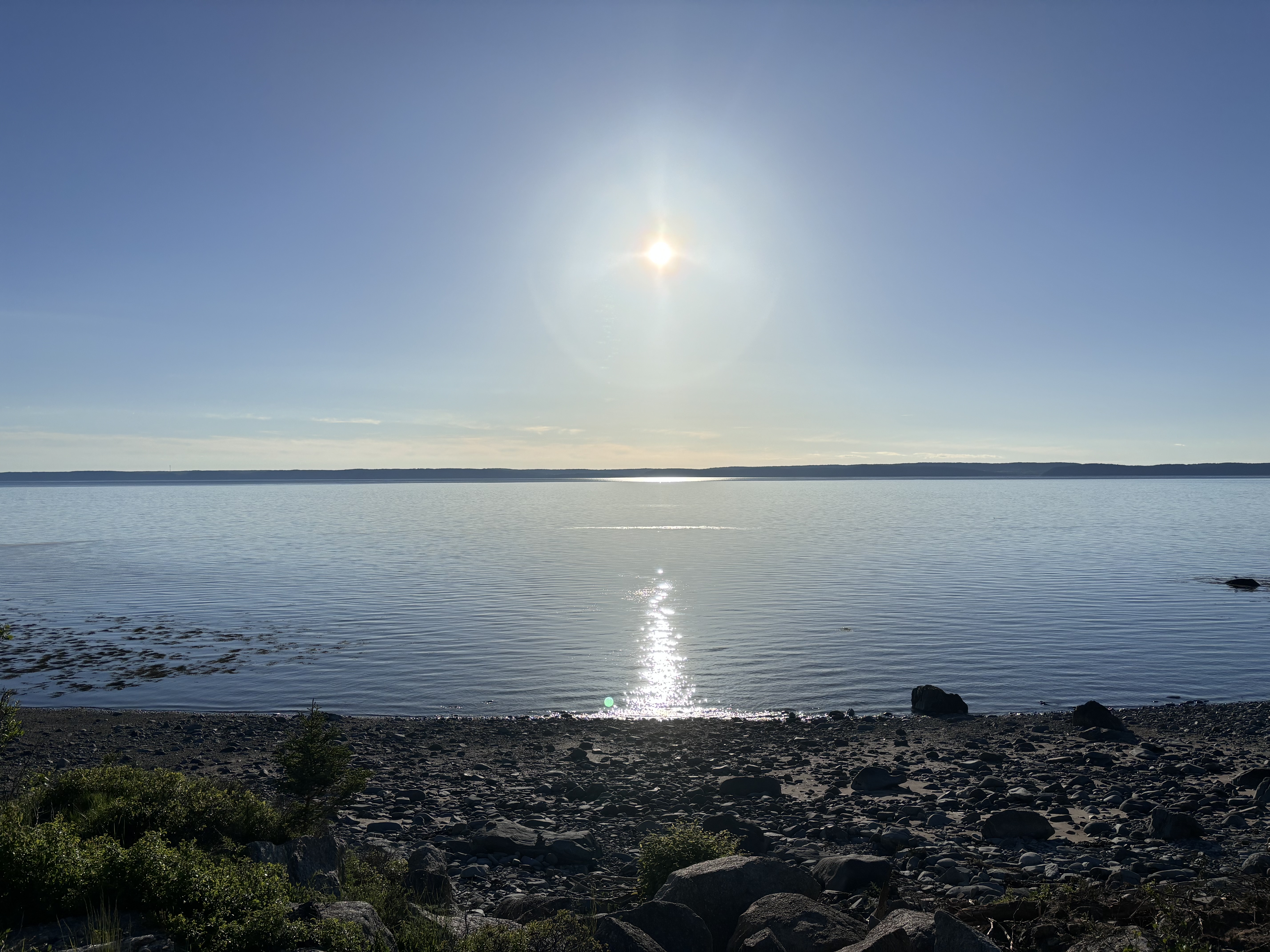 Bright sun over calm bay water
